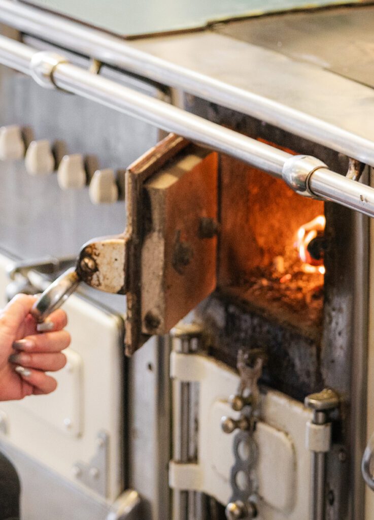 Raabser Stadtkrug Mitarbeiterin schaut in Holzofen Hochformat