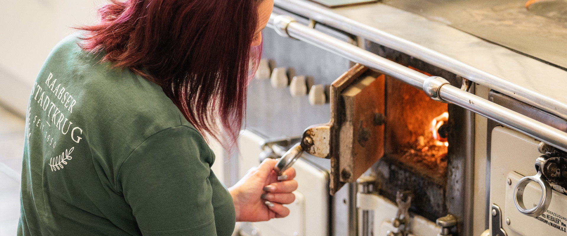 Raabser Stadtkrug Mitarbeiterin schaut in Holzofen